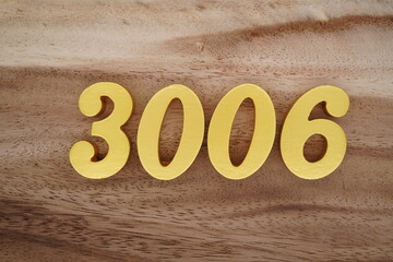 Golden Arabic numerals on a real brown and white wooden floor number 3006