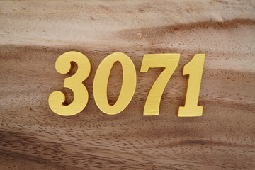 Golden Arabic numerals on a real brown and white wooden floor number 3071