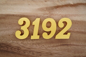 Golden Arabic numerals on a real brown and white wooden floor number 3192