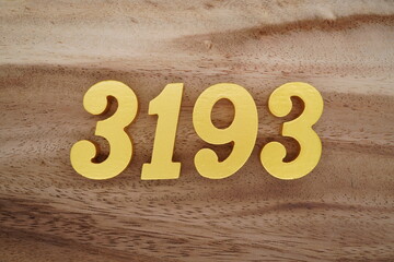 Golden Arabic numerals on a real brown and white wooden floor number 3193