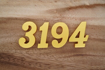 Golden Arabic numerals on a real brown and white wooden floor number 3194