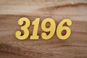 Golden Arabic numerals on a real brown and white wooden floor number 3196