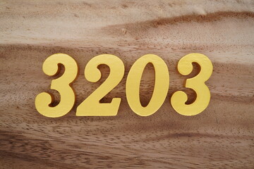 Golden Arabic numerals on a real brown and white wooden floor number 3203
