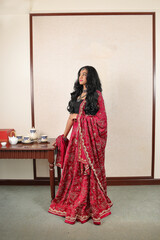 Beautiful young woman wearing Indian lehenga hgagra ankle length skirt dress posing home retro vintage