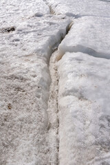  Large crack in permafrost ice revealing dry rocks hidden beneath.