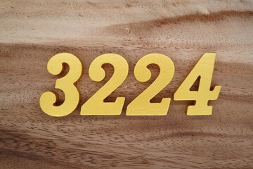Golden Arabic numerals on a real brown and white wooden floor number 3224