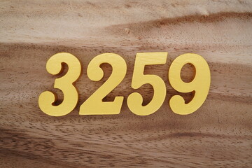Golden Arabic numerals on a real brown and white wooden floor number 3259