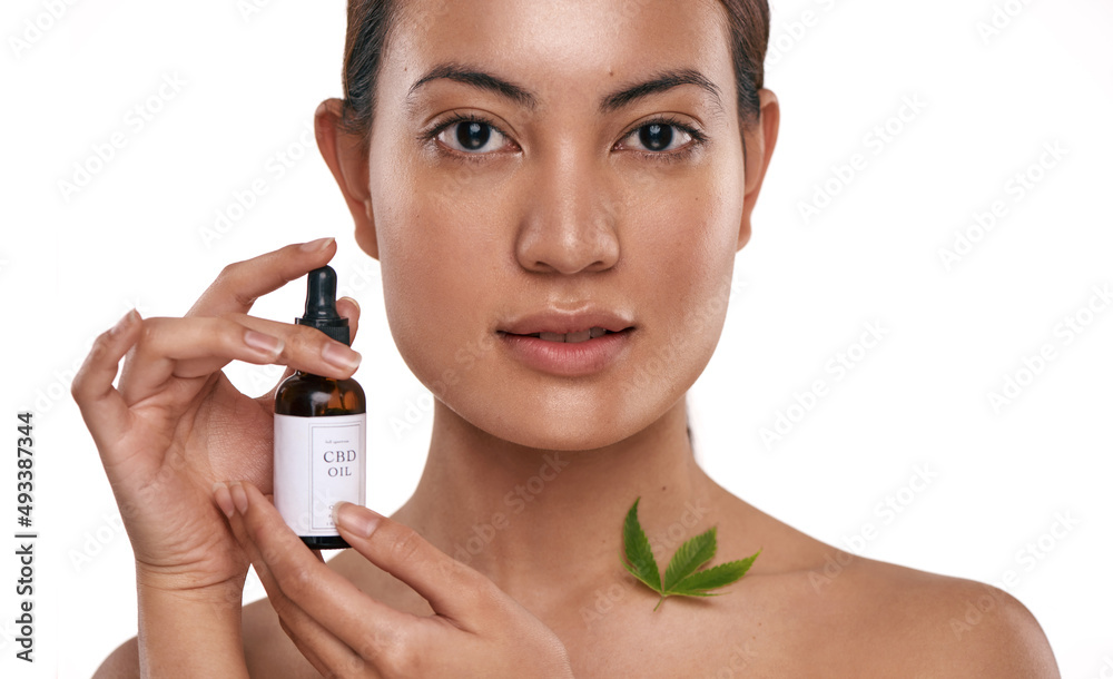 Canvas Prints Natural products will give you healthy skin. Shot of a beautiful young woman holding a bottle of CBD oil against a white background.