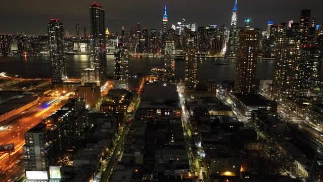 An aerial timelapse by the entrance of the Midtown Tunnel in Long Island City, New York at night. The drone camera dolly in towards Manhattan from the Queens side of the East River.