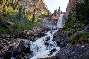 Beautiful waterfall in mountains with. Barskoon waterfall - splashes of Champaign. Travel, tourism in Kyrgyzstan concept.