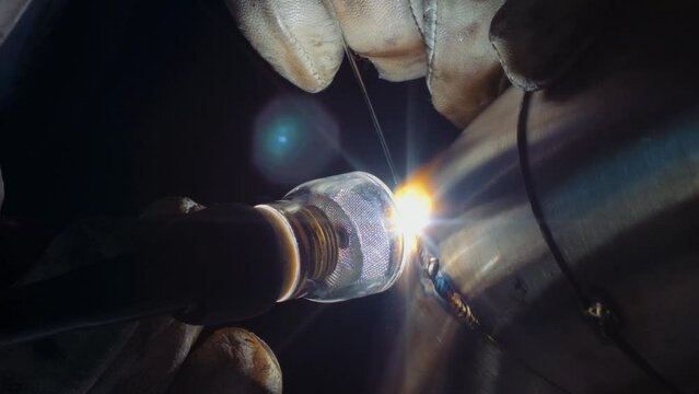 Close up of a fabricator TIG welding stainless steel exhaust pipe with pie cuts. 
Static shot.