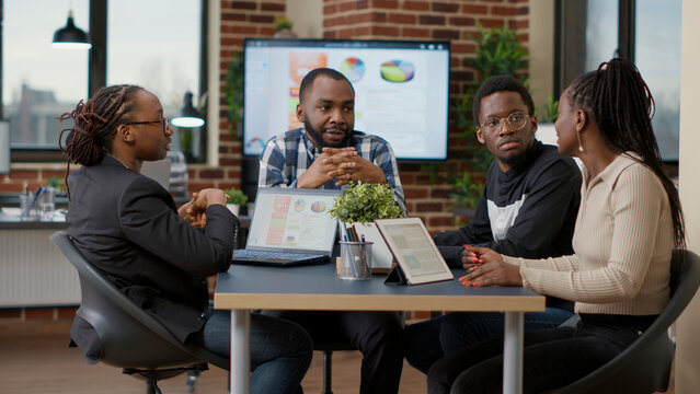 Team of african american businesspeople meeting in boardroom office to discuss strategy and work plan, creating financial project with statistics. Colleagues doing teamwork to analyze sales data.