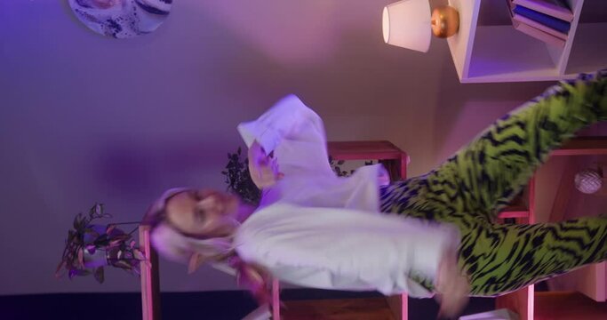 Vertical video of woman recording dance video in living room. Young female student or teenager dancing at home for musical clip. Blogger making music content for channel, wearing elf ears.