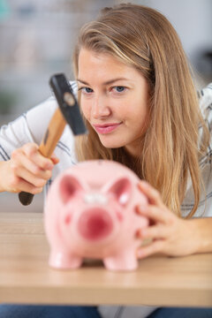 Young Woman Breaking A Piggy Bank