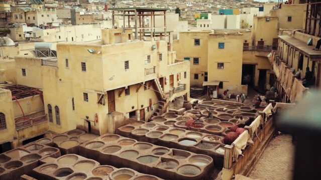 A rooftop view of Local laborers treating garments in vats of dye at a leather tannery in Fez, Morocco, Africa