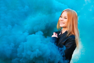 portrait of beautiful smiling girl on a background of blue smoke with copy space