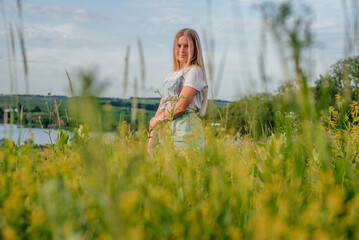 A beautiful young girl among yellow flowers at summer Ukrainian rural lanscape