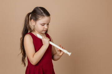 Girl in red dress hold common flute with head down and clamp holes on it, beige background....