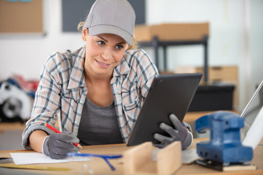 female carpenter worker using tablet while standing in workshop