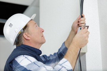 a mature electrician holding cables