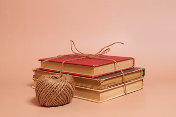 A stack of old battered books tied with jute rope, a coil of jute rope