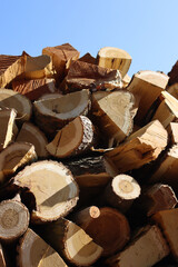 Close-up of chopped firewood against blue sky on a sunny day. Firewood stacked and prepared for winter. Pile of logs 