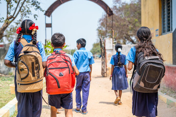 Back view shot of group of teenager kids in unifrom going home from school after classes - concept...
