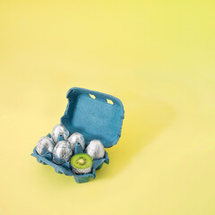 Creative Easter concept of cardboard box of eggs painted in silver aluminum foil and one cut in...