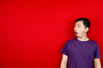 Obraz premium With a surprised face the Asian man showed an empty space for content. Advertising model concept. red background.