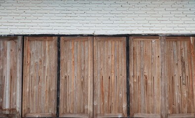 An old wooden window is installed in a beautiful white brick wall to serve as a background.