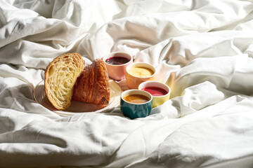 Croissant with different toppings in jars, jams in a plate on a white sheet. Hard light