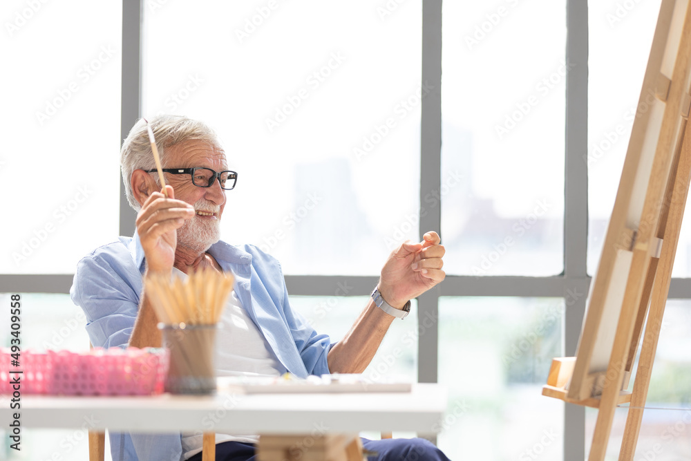 Wall mural senior man painting a picture from paintbrush in free time