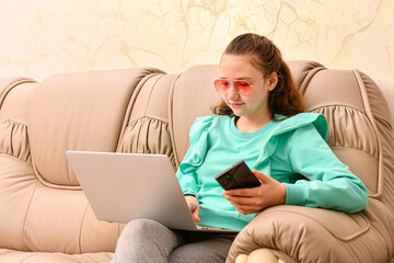 A girl with a laptop and a smartphone in her hand takes online orders.