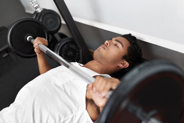 Fototapeta na wymiar Pump that iron. A young ethnic man exercising in the gym.