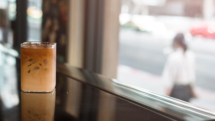 Ice coffee on a wooden table with cream being poured into it showing the texture and refreshing look of the drink