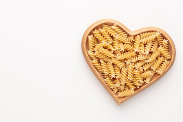 Pasta in a heart shaped wood bowl.