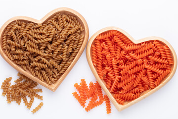 Red lentil fusilli pasta in a heart shaped wood bowl.