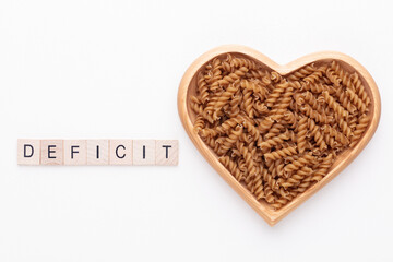 Whole grains fusilli pasta in a heart shaped wood bowl.