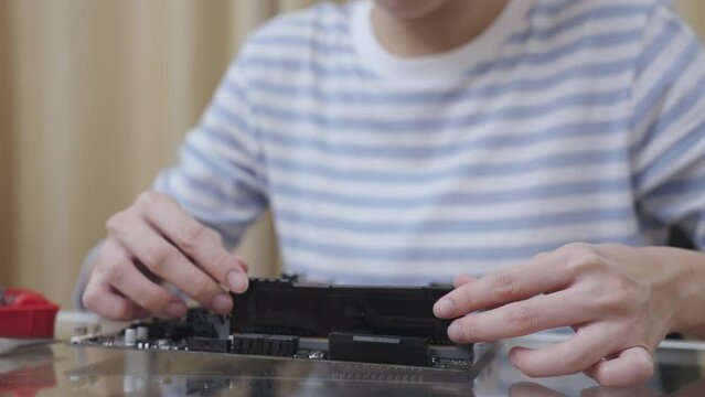Close-up of a woman removing Random Access Memory (RAM) from a computer motherboard.