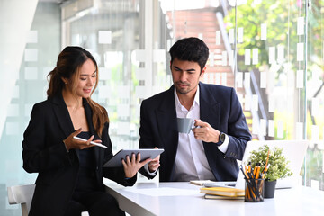 Two successful business people are discussing on business issue in modern office.