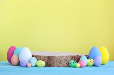 Easter colorful eggs with wooden empty platform on yellow background.
