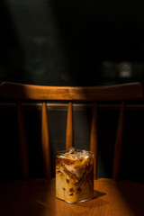 Ice coffee on a wooden table with cream being poured into it showing the texture and refreshing look of the drink