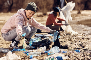 Female volunteer cleaning lake area from the trash.