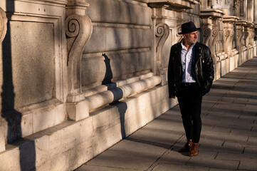 Adult man in hat and leather jacket against wall on street. Madrid, Spain