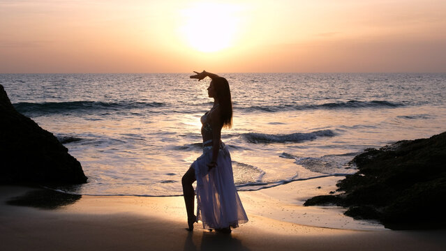 Woman dances to the sun wearing arabic dance costume. Fertility concept. Exotic beauty.