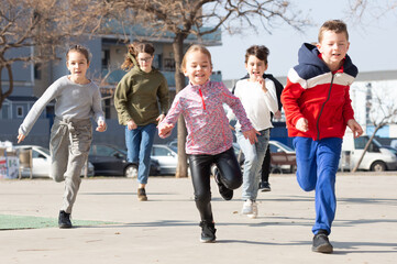 Large group of playful children running together at urban landscape