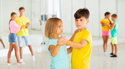 Kids formed pairs and dancing waltz together in studio.