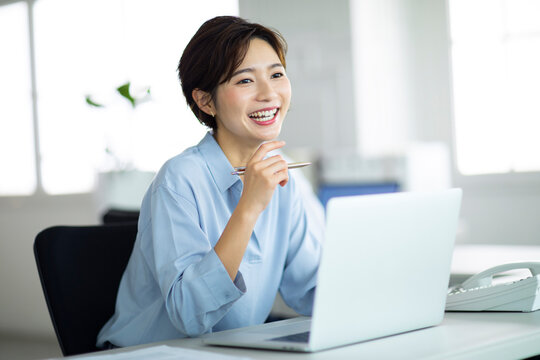 デスクで笑顔で仕事をする女性