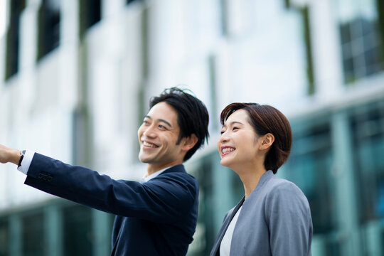 横に並び指を指すビジネススーツの男女