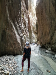 A girl in a narrow mountain gorge Karadakh with sunlight in Dagestan. Russia, June 2021.